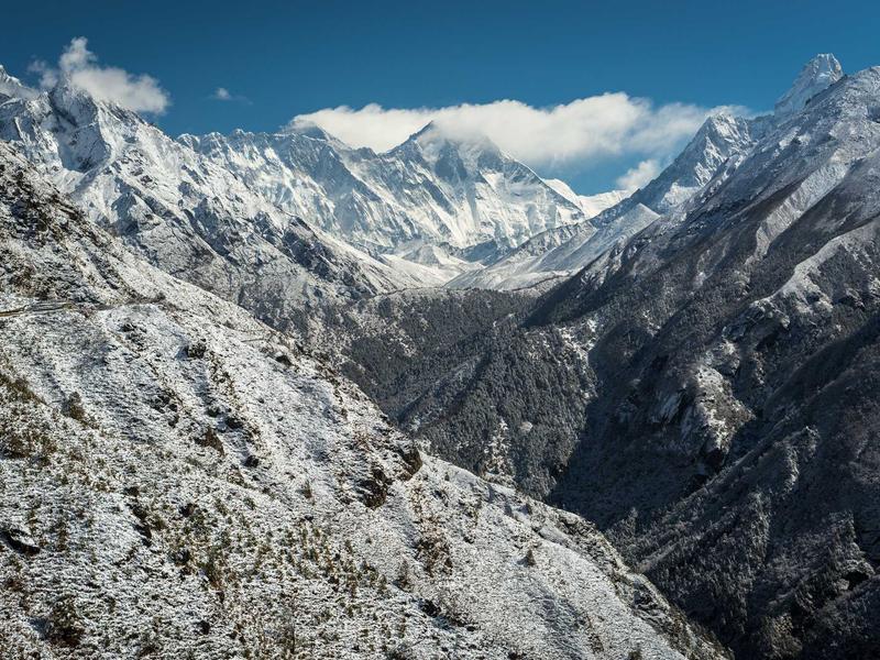 Hyper-realistic wide shot of a majestic snowy mountain peak under a clear blue sky, 8k resolution